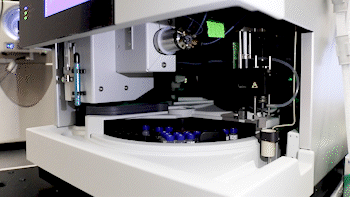 Robotic arm picks up sample from a rotating tray.