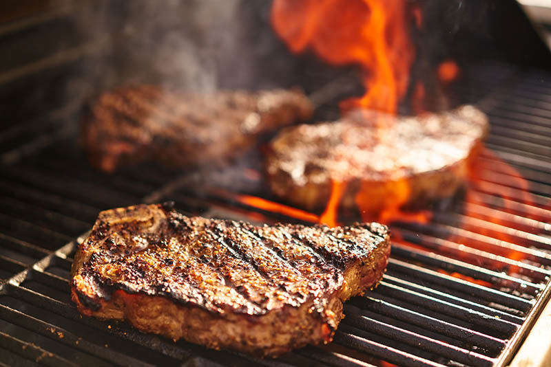 steaks cooking on a grill