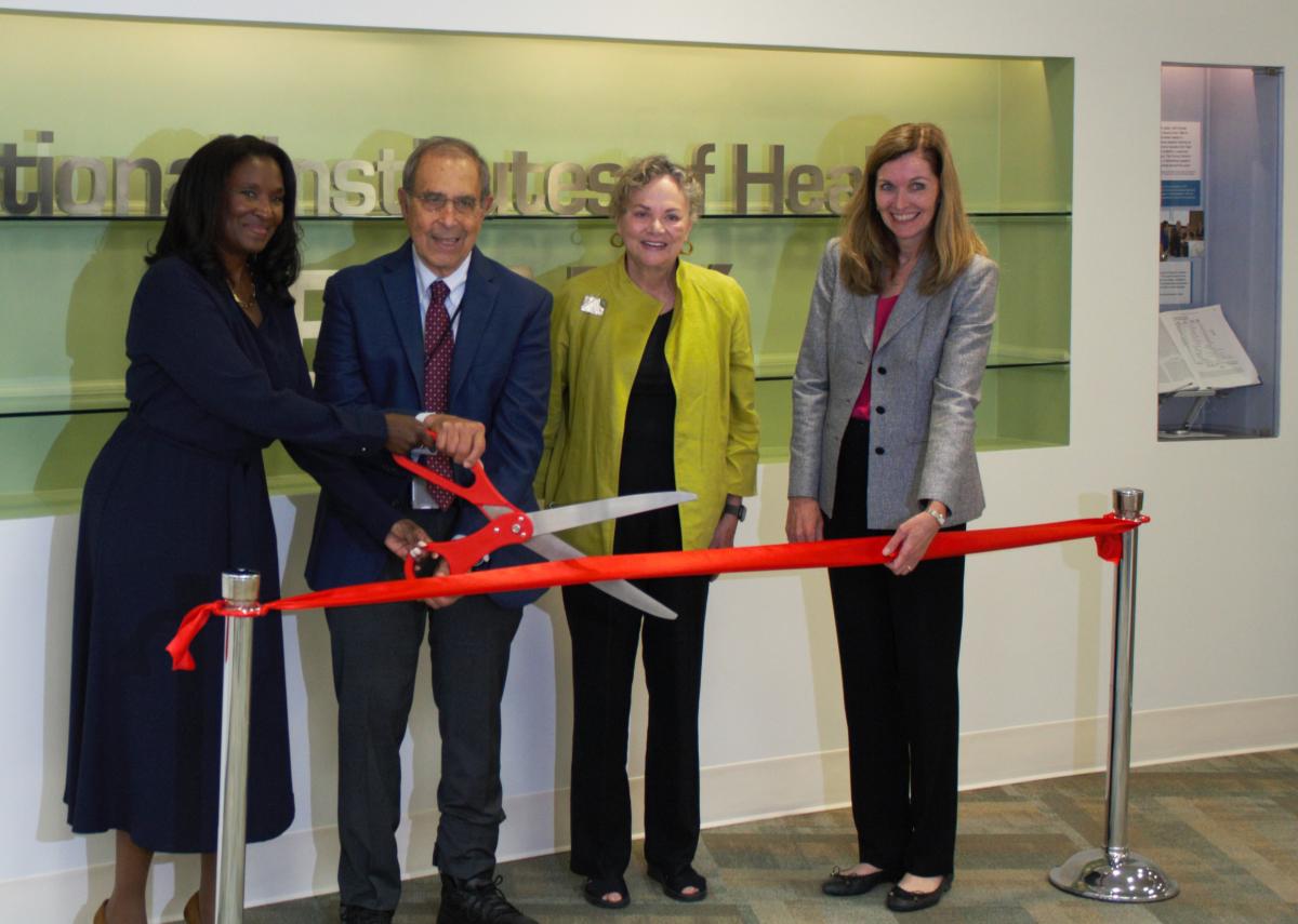 John Gallin cutting a red ribbon with giant scissors