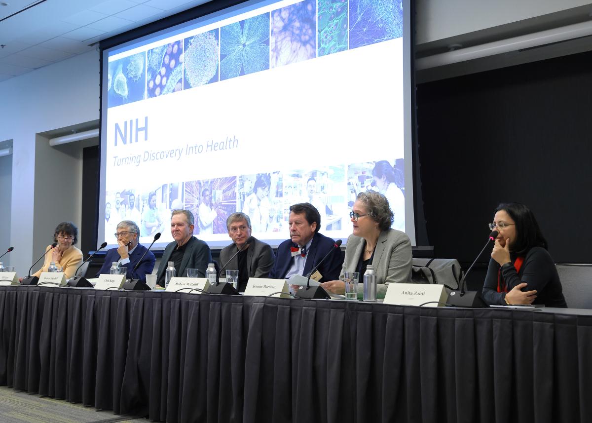 Monica Bertagnolli, Bill Gates, and other leaders sitting behind a table