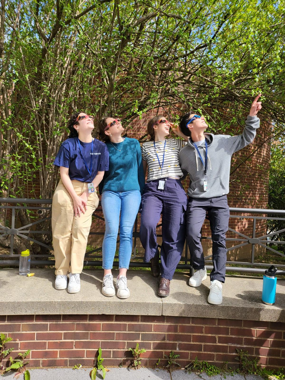 four young scientists watching solar eclipse with glasses