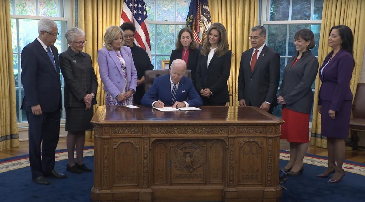 President Joe Biden signing a bill in the oval office with women leaders