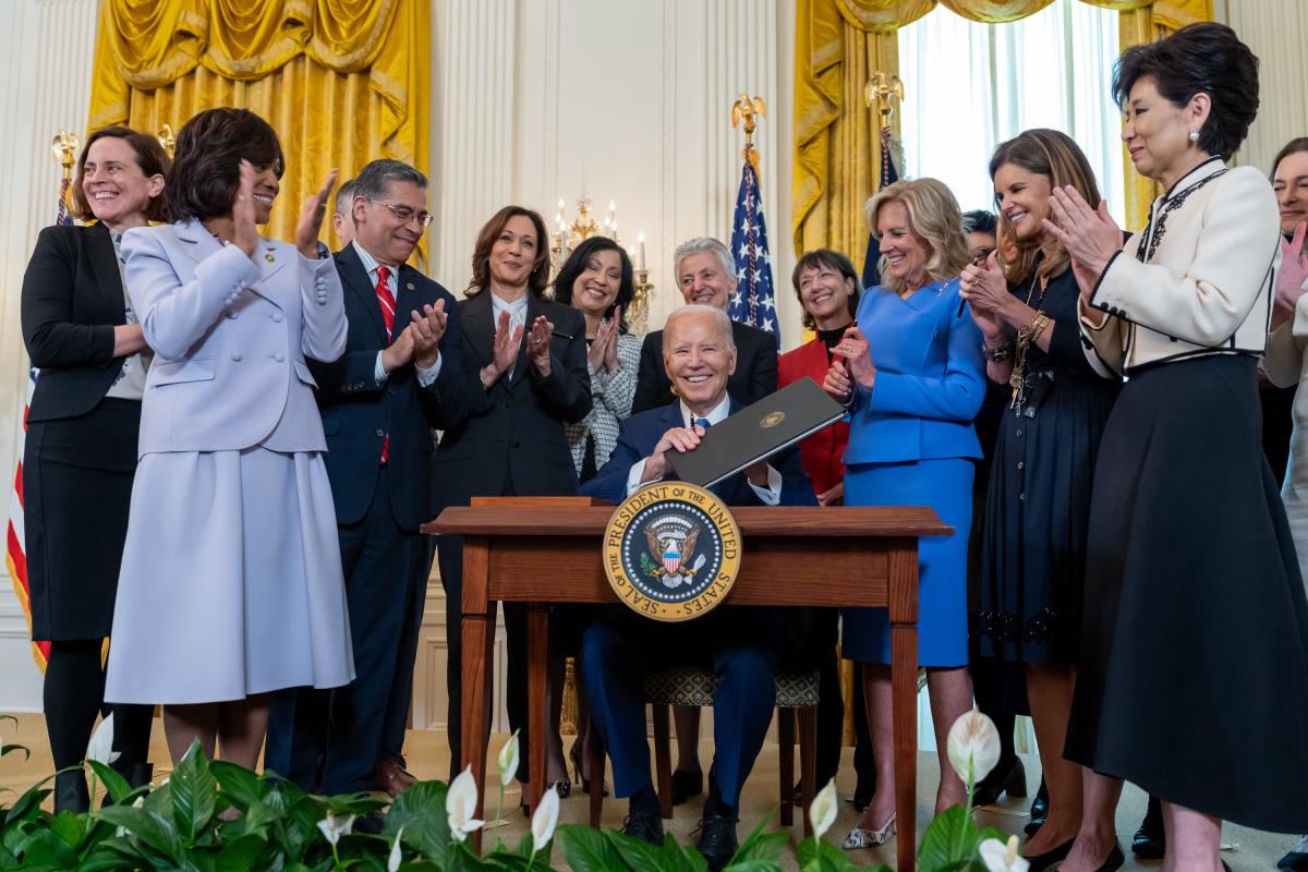 President Joe Biden signing a bill in the oval office with women leaders