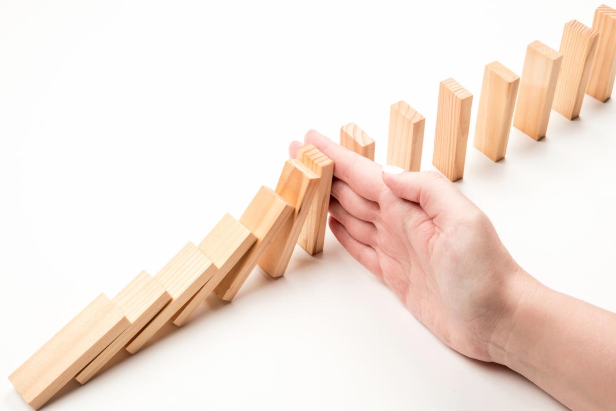 hand stopping dominos from falling