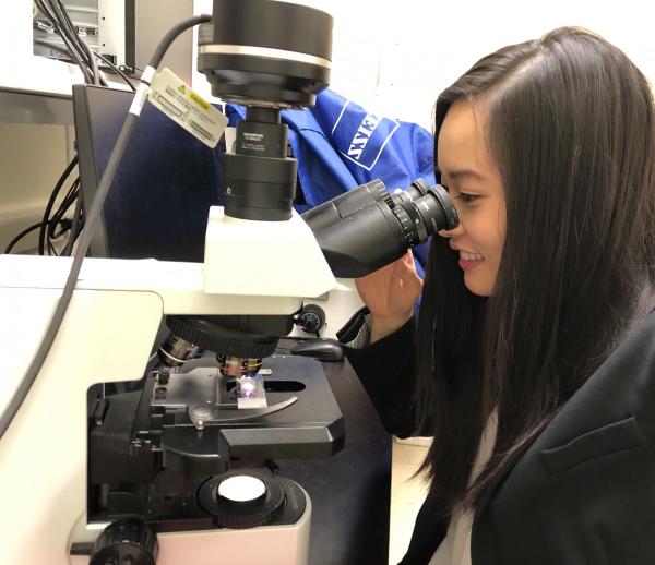 postbac IRTA Lindsey Jay examining a slide using a microscope