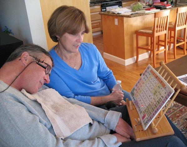 A man with ALS uses a head mounted laser pointer to communicate with his wife by pointing to letters and words on a communication board