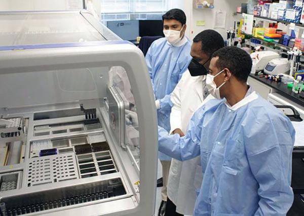 Dr. Agbor-Enoh and members of his staff prepare to use a machine in their lab