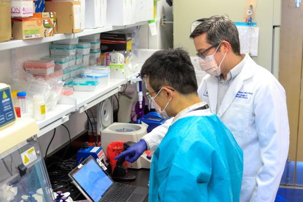 two men in a lab wearing face masks