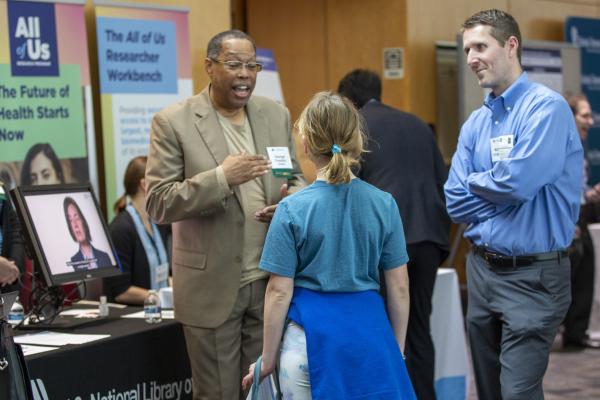 father and daughter speaking to a researcher at a poster booth