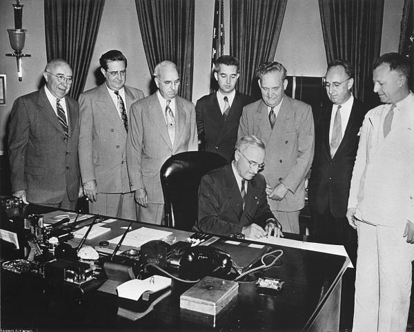 Historical photo of Harry Truman signing a document