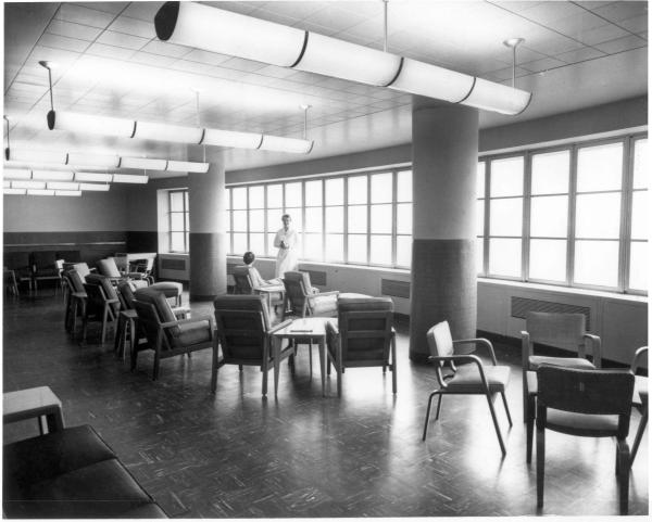 Black and white image of NIH Clinical Center solarium with a doctor and patient