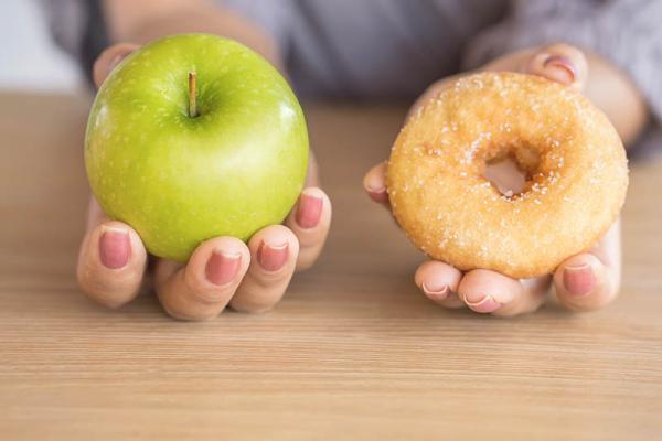 person holding an apple and a donut