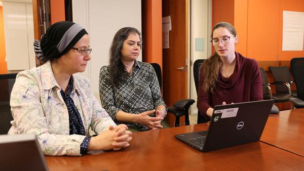 Dr. Shahinaz Gadalla discusses recent findings with the two members of her lab, postdoctoral cancer prevent fellow Kyra Mendez (right) and medical geneticist Maryam Rafati (middle)
