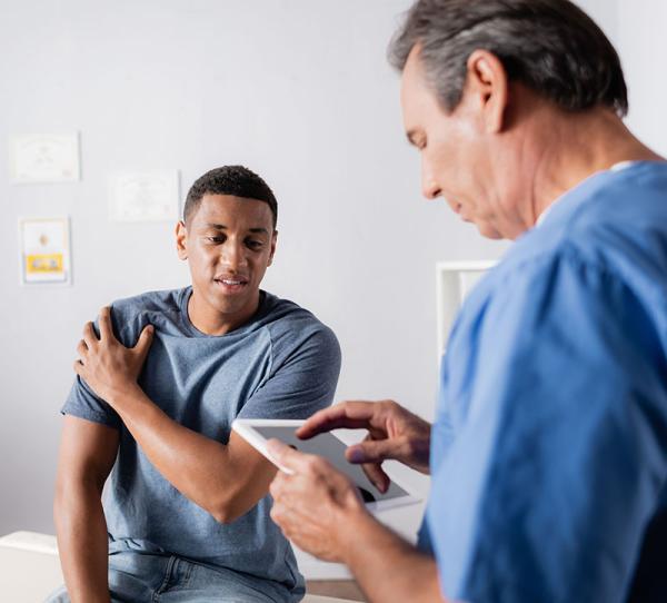 patient with shoulder injury talks with doctor