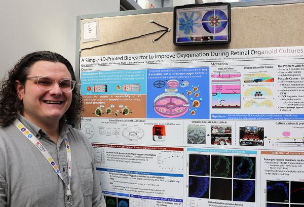 IRP graduate student Kyle Schwab poses with his scientific poster