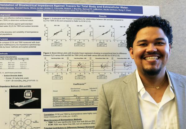 IRP postbaccalaureate fellow Gabriel Sanchez poses with his poster at Postbac Poster Day