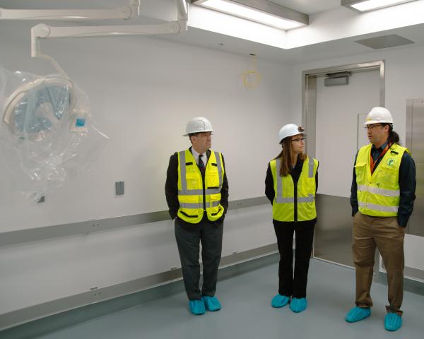 three people in hard hats and neon vests in a new surgical facility