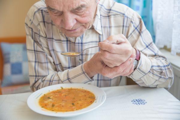 older man having difficulty eating soup