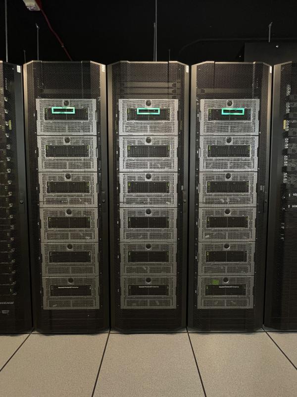 three tall narrow computer servers with glowing turquoise lights