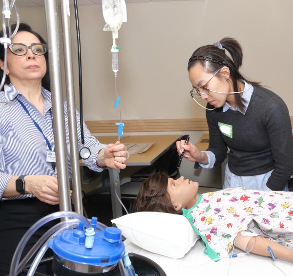 Mabel Gómez (left), simulation facilitator and educator, monitors IV fluids during a simulation training.