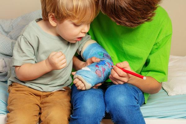 a child writing on another child's arm cast