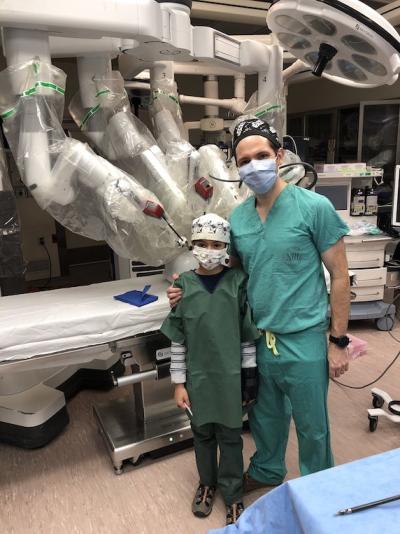 father and son stand in scrubs in robotic surgical suite