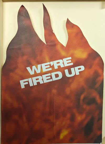 protest sign with flames on it and "we're fired up" text